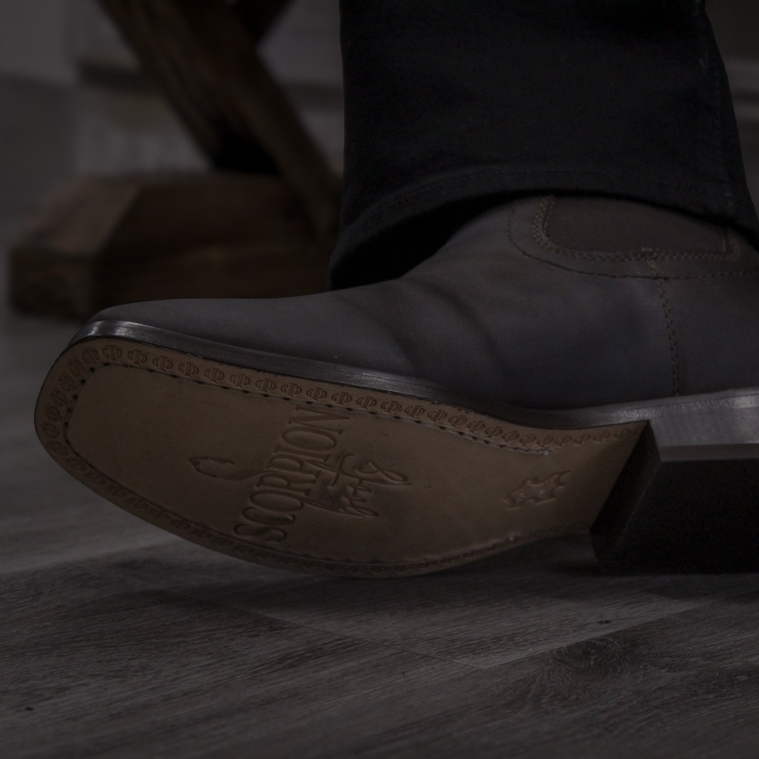 A person wearing dark brown high-top boots with a lace-up closure, standing in a room with light-colored flooring.